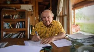 Imagem de Yvon Chouinard, bilionário que doou fortuna, sentado à mesa.