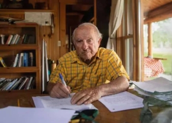 Imagem de Yvon Chouinard, bilionário que doou fortuna, sentado à mesa.