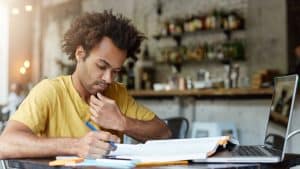 Homem negro, de camisa amarela, estudando.