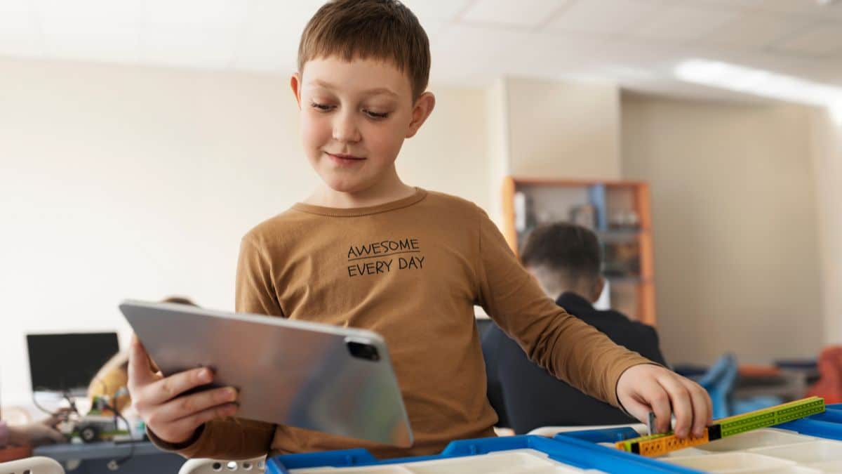 Criança aprendendo sobre como reconhecer fake news com tablet em sala de aula.