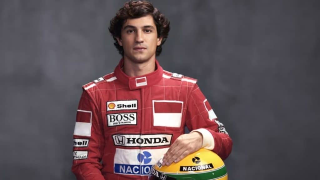 Gabriel Leone, ator da série sobre Ayrton Senna na Netflix, sentado segurando o capacete do piloto, representando o ícone da Fórmula 1.