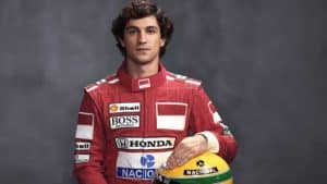 Gabriel Leone, ator da série sobre Ayrton Senna na Netflix, sentado segurando o capacete do piloto, representando o ícone da Fórmula 1.