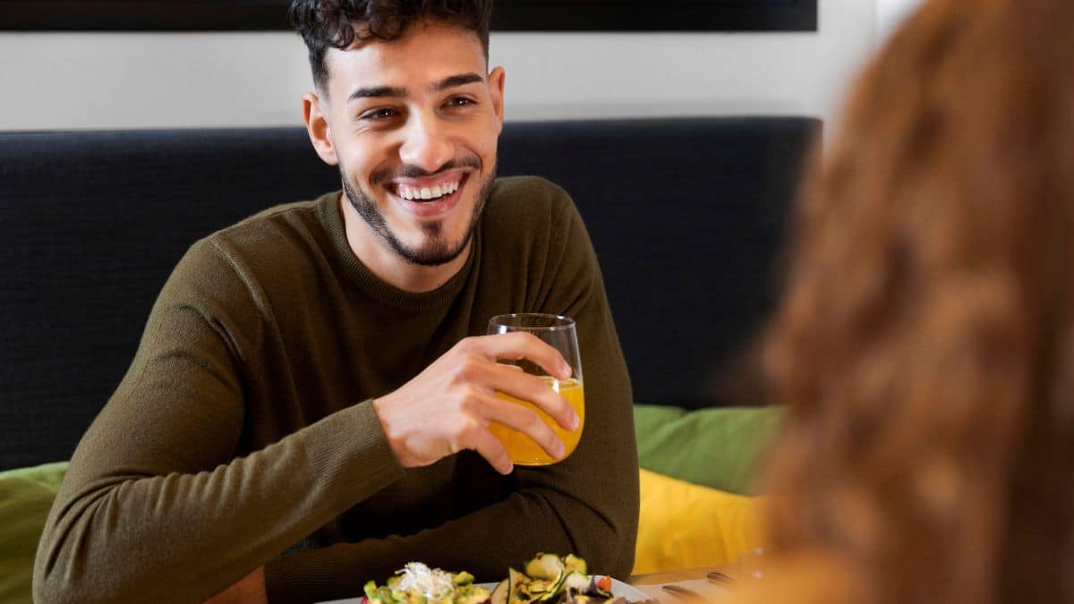 Homem feliz comendo enquanto toma uma bebida.