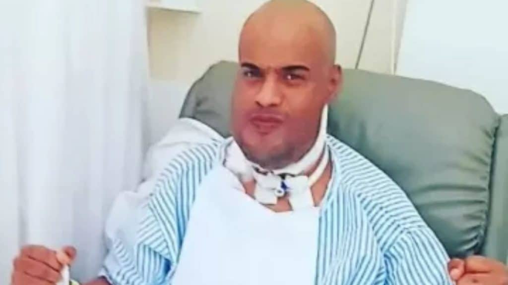 Thiago dos Reis vestido com roupa hospitalar após cirurgia de retirada da língua.