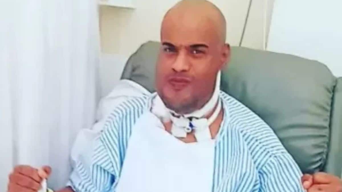 Thiago dos Reis vestido com roupa hospitalar após cirurgia de retirada da língua.