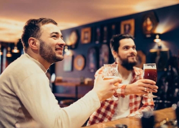 Imagens de dois homens brancos bebendo em um bar.