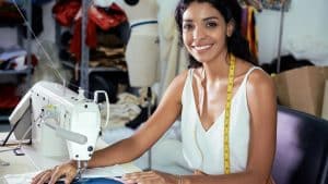 Mulher sorrindo em atelier de costura, destacando o setor da moda e representando o evento do IEL Ceará.