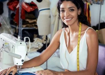 Mulher sorrindo em atelier de costura, destacando o setor da moda e representando o evento do IEL Ceará.