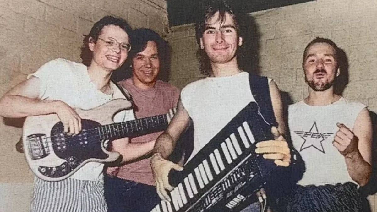 A imagem mostra um grupo de quatro homens posando com instrumentos musicais, incluindo um teclado estilo keytar e uma guitarra. Um dos membros veste uma camiseta com o logotipo "FEX", sugerindo que eles possam ser da banda FEX, a responsável pela canção "Subways of Your Mind", recentemente identificada como a "música mais misteriosa da internet".