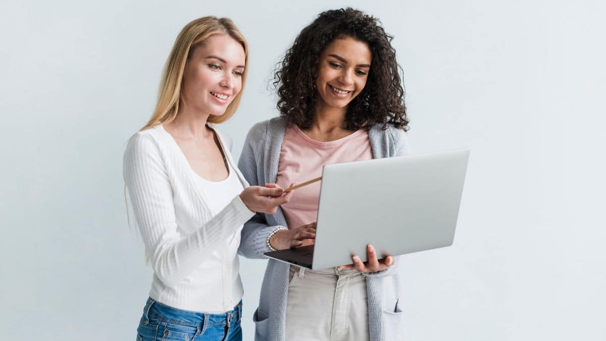 Duas jovens mulheres analisando algo em um laptop.