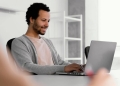 Homem negro sentado e trabalhando em frente ao computador.