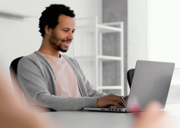 Homem negro sentado e trabalhando em frente ao computador.