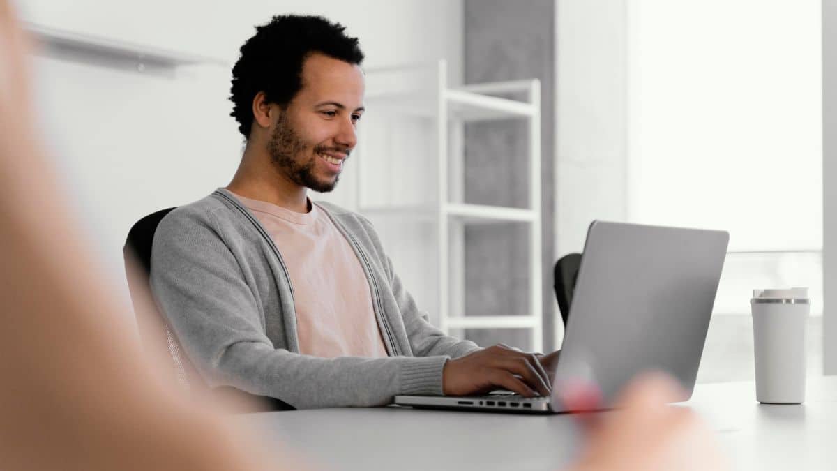 Homem negro sentado e trabalhando em frente ao computador.