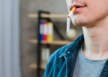 Imagem de um homem com cigarro quebrado na boca.