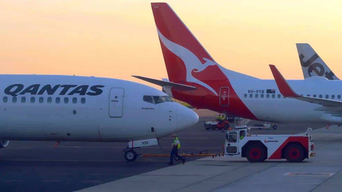 Aeronaves da Qantas Airways estacionadas no aeroporto ao entardecer, destacando a expansão da companhia aérea com voos de longa duração.