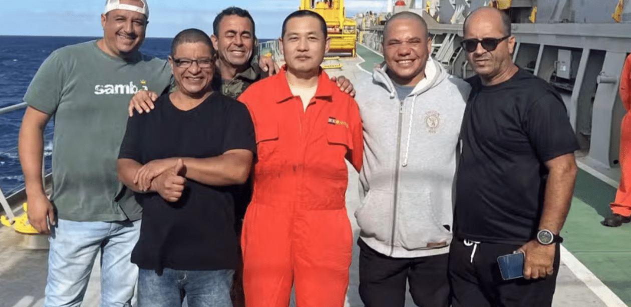Resgate de pescadores brasileiros por tripulação chinesa após naufrágio no mar, em momento de confraternização no navio.