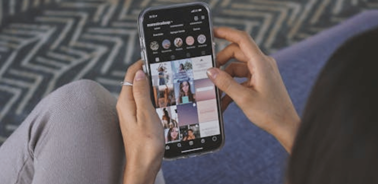 Pessoa rolando o feed do Instagram no celular, sentada em ambiente interno