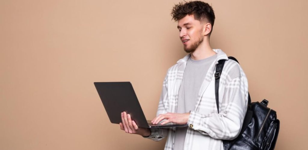 Jovem com laptop e mochila, representando estudo, trabalho remoto ou aprendizado digital.