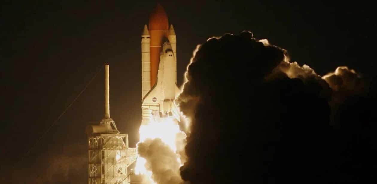 ançamento noturno de um foguete da NASA, iluminando o céu com sua propulsão e deixando uma grande nuvem de fumaça na decolagem.