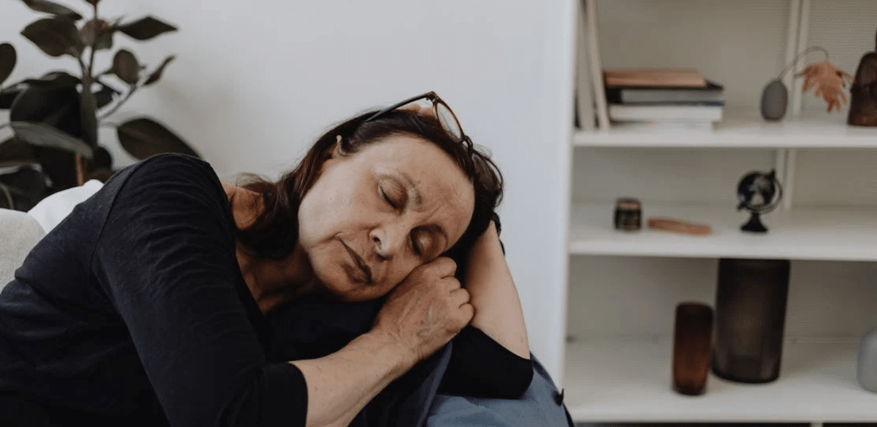 Mulher cochilando sentada durante a tarde, representando como cochilos podem melhorar o foco se forem bem planejados.