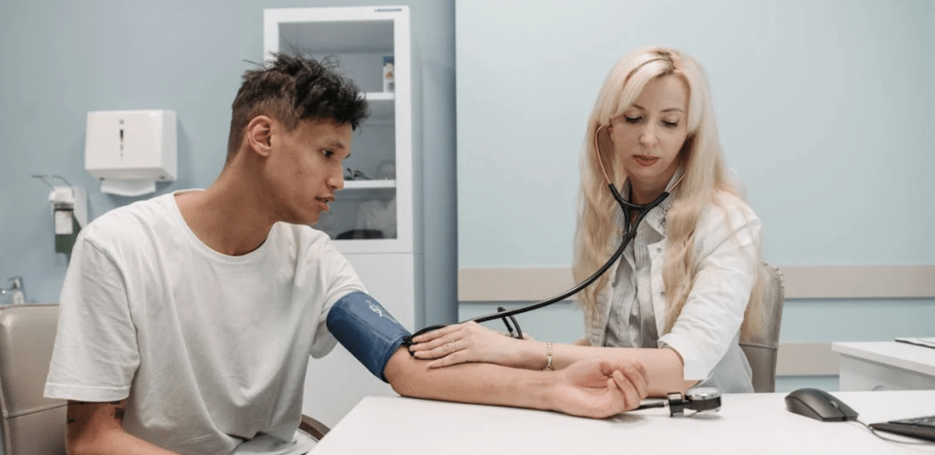 Médico verifica pressão arterial de paciente em consulta para avaliar sinais de hipertensão emocional.