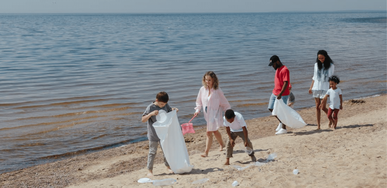 Famílias e crianças participam de mutirão de limpeza em praia, recolhendo lixo e promovendo consciência ambiental no Canal da Barra.