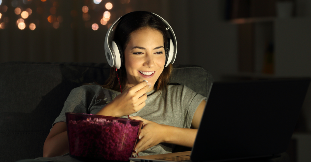 Pessoa relaxando em casa enquanto assiste a filmes leves e inspiradores.