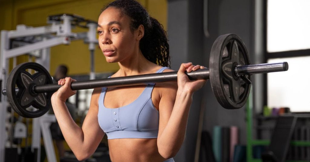Mulher levanta pesos durante treino, representando os efeitos positivos da memória muscular