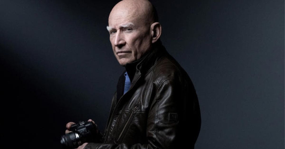 Sebastião Salgado segurando câmera fotográfica em retrato de estúdio
