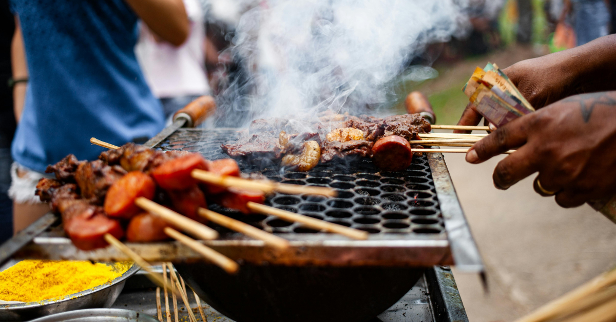 Pessoas assando carne na brasa em uma churrasqueira