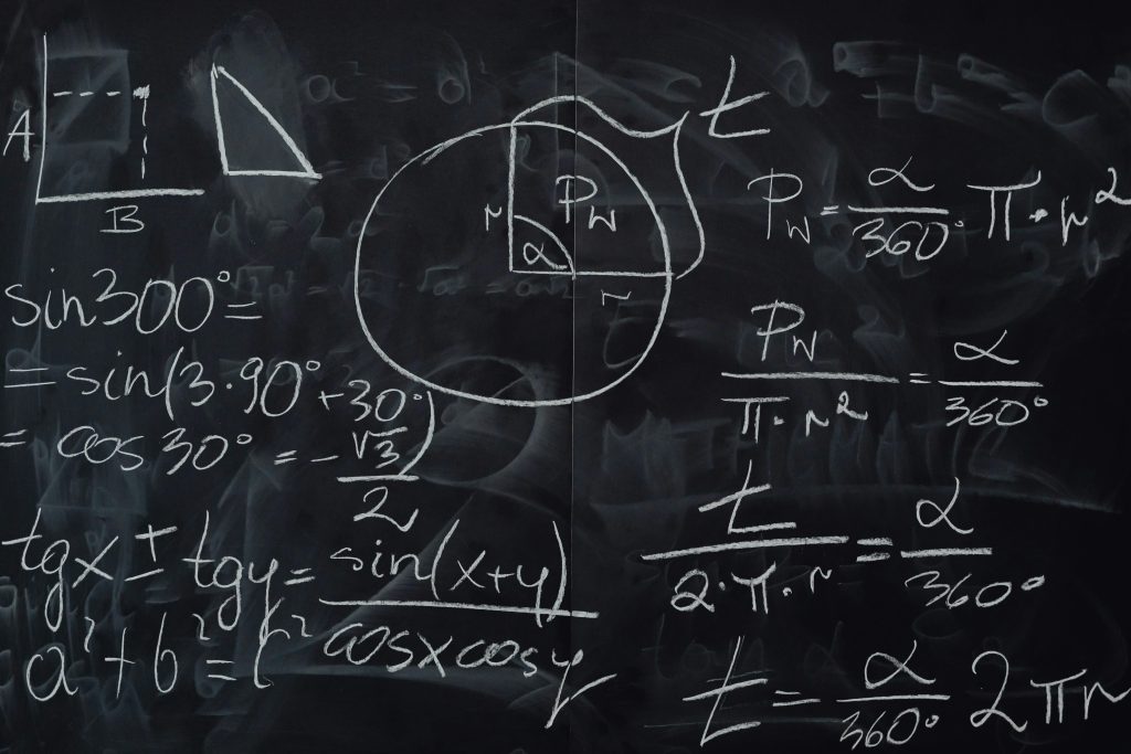 Quadro negro coberto por operações matemáticas escritas com giz branco.