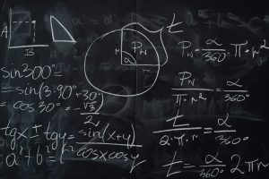 Quadro negro coberto por operações matemáticas escritas com giz branco.
