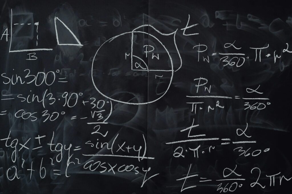 Quadro negro coberto por operações matemáticas escritas com giz branco.