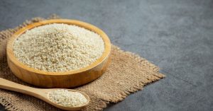 Fibras do psyllium em tigela de madeira com colher sobre tecido rústico