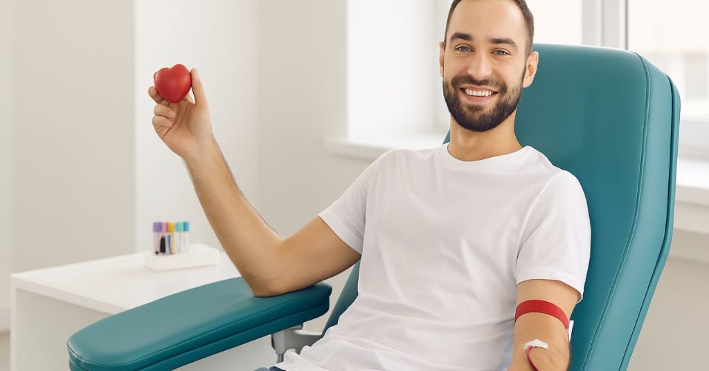 Homem doando sangue com coração na mão esquerda