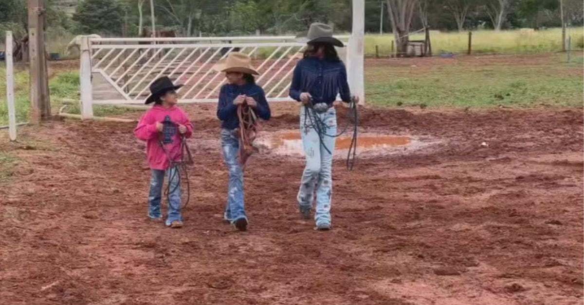 Irmãs cavaleiras caminhando em área de treinamento rural