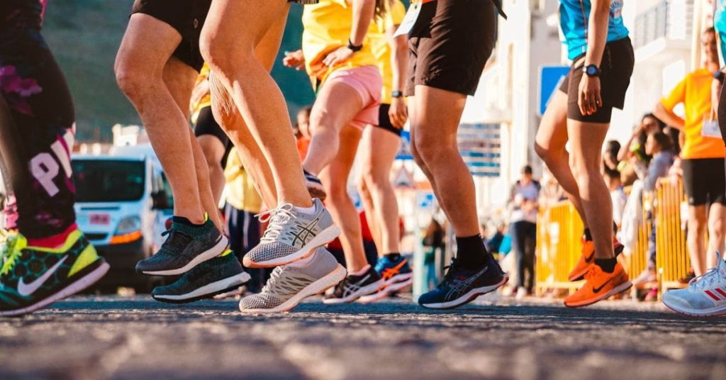 Pessoas usando tênis de corrida durante prova de rua em dia ensolarado