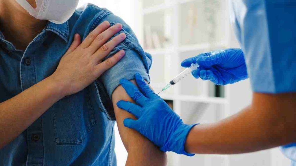 Profissional da saúde aplica vacina contra o câncer em paciente no Reino Unido, representando o novo método de imunoterapia com a vacina contra 15 tipos de câncer no Reino Unido.