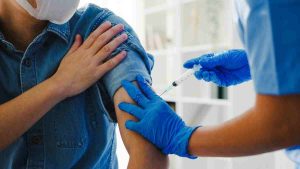 Profissional da saúde aplica vacina contra o câncer em paciente no Reino Unido, representando o novo método de imunoterapia com a vacina contra 15 tipos de câncer no Reino Unido.