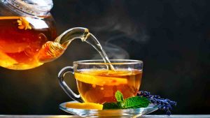 Chá quente sendo servido em xícara de vidro com ervas naturais — chás para desinflamar