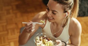 Mulher com roupa de treino se alimenta antes do exercício, mostrando que alimentação e sono são alternativas aos suplementos pré-treino