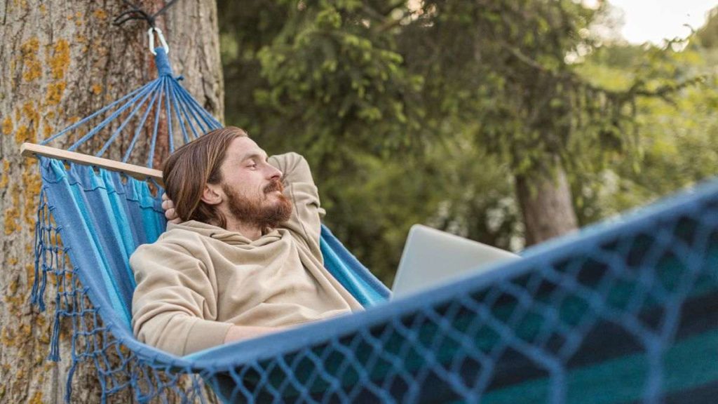Homem relaxando em rede ao ar livre, representando os benefícios do silêncio para a saúde mental