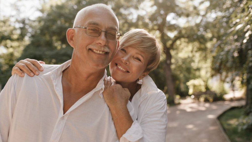 Casal idoso feliz em ambiente natural representando o menor risco de demência nas novas gerações.