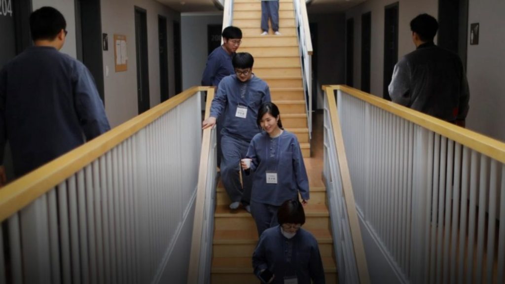 participantes da prisão voluntária na Coreia do Sul caminhando pelos corredores internos do retiro