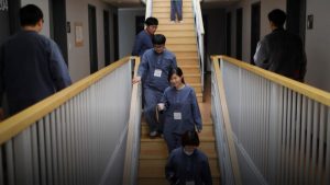 participantes da prisão voluntária na Coreia do Sul caminhando pelos corredores internos do retiro