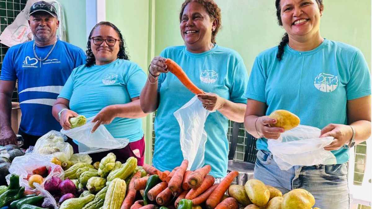 Agricultores e voluntários do projeto Meta MOH Fome exibem alimentos frescos em feira comunitária, simbolizando segurança alimentar no Brasil.