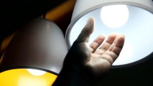 isenção da conta de luz - Uma mão estendida em direção a uma lâmpada acesa, simbolizando a isenção da conta de luz para famílias de baixa renda.