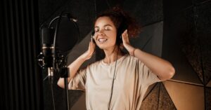 mulher cantando com fones de ouvido em estúdio, representando os benefícios do canto.