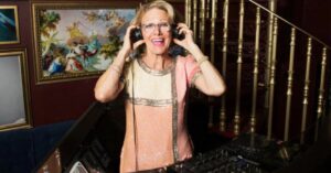 DJ idosa sorri enquanto comanda as pick-ups em Estocolmo.