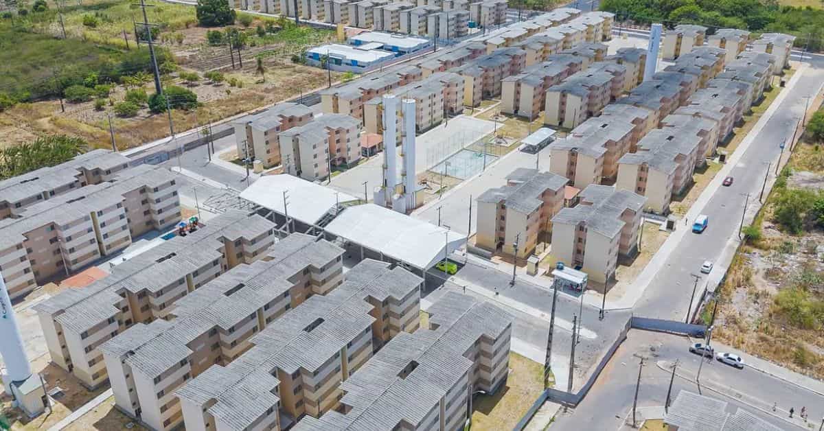 Conjunto habitacional do programa Minha Casa Minha Vida visto de cima, com prédios populares e área de convivência.